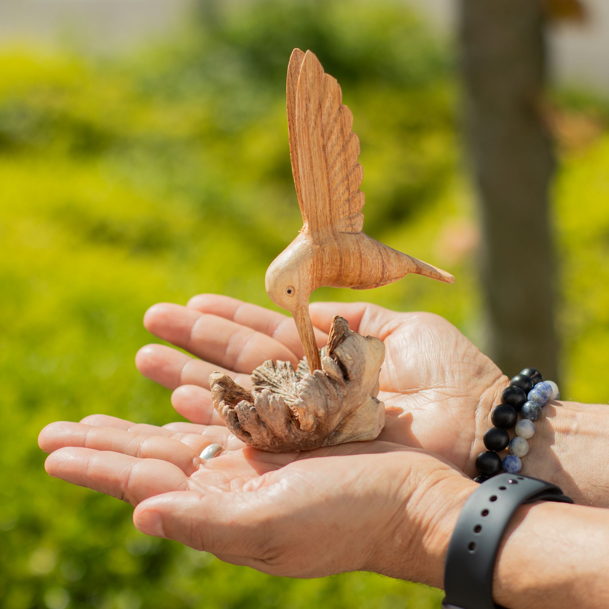 Handgefertigte Skulptur eines Kolibris, der Nektar aus einer Baumverwachsung trinkt
